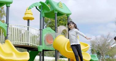 Slow motion shot, Two Asian cute girl slowly play with extend the arms and smile with happy together at playground video