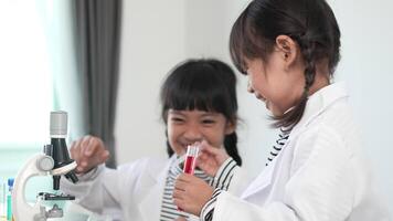 Slow motion shot, Two asian siblings wearing coat use test tube and microscope for experimenting with liquids, while studying science chemistry with fun video