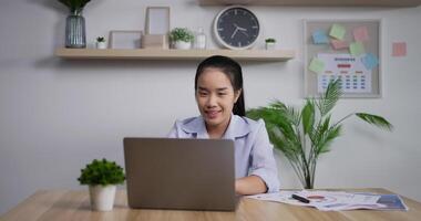 retrato de empresária asiática feliz com computador portátil trabalhando em home office. jovem estudante freelancer usando laptop estudando online trabalhando em casa. video