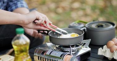 close-up de fritar um saboroso ovo frito em uma panela quente no acampamento. cozinhar ao ar livre, viajar, acampar, conceito de estilo de vida.