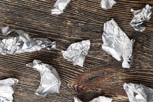 crumpled pieces of foil from chocolate on a wooden table photo