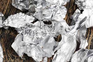 crumpled pieces of foil from chocolate on a wooden table photo