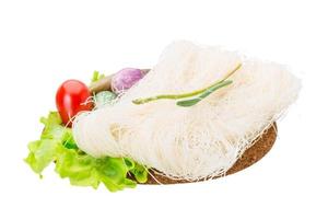 Raw rice noodles on wooden plate and white background photo