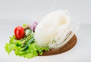 Raw rice noodles on wooden plate and white background photo