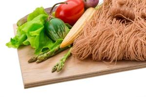 Raw rice noodles on wooden plate and white background photo