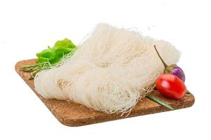 Raw rice noodles on wooden plate and white background photo