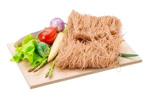 Raw rice noodles on wooden plate and white background photo