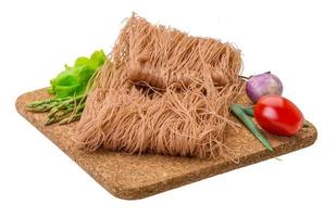 Raw rice noodles on wooden plate and white background photo