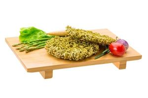 Green raw noodles on wooden plate and white background photo