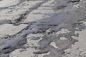 a bad road with poorly repaired potholes and pits photo