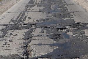 a bad road with poorly repaired potholes and pits photo