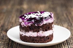 chocolate cake with cream covered with purple berry jam photo