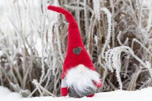 a small toy sitting in the snow in red clothes photo