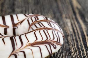 a fresh doughnut covered with white chocolate , closeup photo