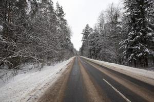 the road in the winter season, the roadway is covered with melted snow photo