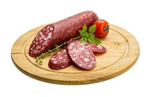 Salami sausages on wooden plate and white background photo