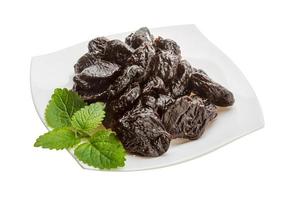 Dried plums on the plate and white background photo