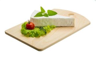 Brie cheese with thyme on wooden plate and white background photo