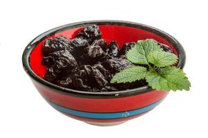 Dried plums in a bowl on white background photo