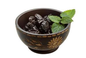 Dried plums in a bowl on white background photo