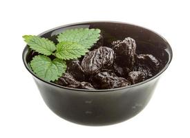 Dried plums in a bowl on white background photo