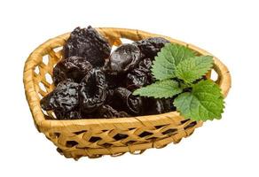 Dried plums in a basket on white background photo