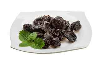 Dried plums on the plate and white background photo