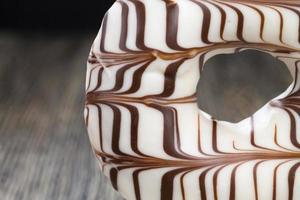 a fresh doughnut covered with white chocolate , closeup photo