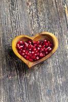 fresh pomegranate seeds in a heart shaped bowl photo