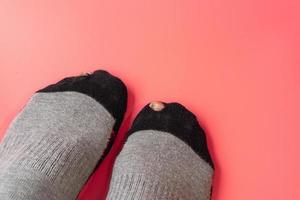 Socks with a hole on a light pink background.Broken sock with a hole. photo