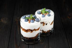 Homemade layered dessert with fresh blueberries, cream cheese or yogurt, granola on rustic background. photo