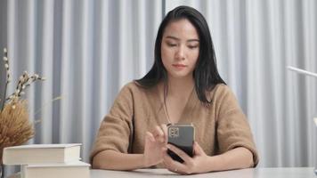 Cheerful girl checks social media on her phone and surfs online apps. video