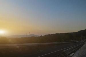 Asphalt road and mountain landscape at sunset sky background. Country road and mountains. photo