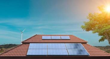 panel solar en el techo de una casa con turbinas eólicas alrededor. fotovoltaica, fuente de electricidad alternativa. foto