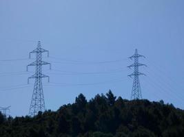 Silhouettes of high voltage metal towers in the mountains photo
