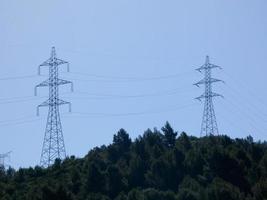 Silhouettes of high voltage metal towers in the mountains photo