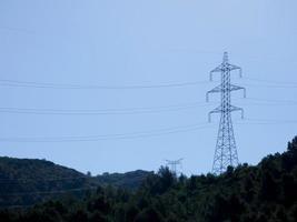 Silhouettes of high voltage metal towers in the mountains photo