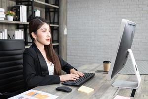 Portrait of pretty business woman using computer at workplace in an office. positive business lady smiling looking into screen of computer. photo