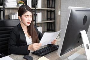 Portrait of pretty business woman using computer at workplace in an office. positive business lady smiling looking into screen of computer. photo