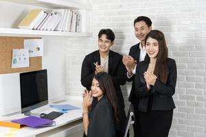 equipo de negocios feliz aplaudiendo. gente de negocios trabajando juntos en proyectos y lluvia de ideas en la oficina. amables empleados diversos felicitando a la mujer de negocios por los logros empresariales. foto