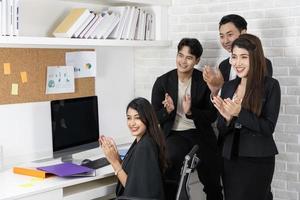 equipo de negocios feliz aplaudiendo. gente de negocios trabajando juntos en proyectos y lluvia de ideas en la oficina. amables empleados diversos felicitando a la mujer de negocios por los logros empresariales. foto