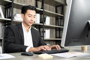 Portrait of business man using computer at workplace in an office. positive business man smiling looking into screen of computer. photo