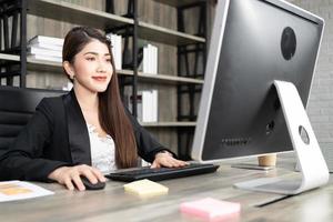 Portrait of pretty business woman using computer at workplace in an office. positive business lady smiling looking into screen of computer. photo