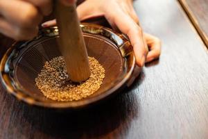 Japanese sesame grinding bowl and wooden stick. Wooden bowl with white sesame for grinding on wooden table. small stick for Japanese pork cutlet photo