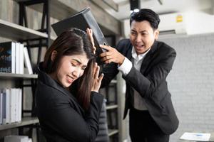 Emotional colleagues fighting in office. Workplace conflict. Angry boss. Man as a boss in the office is violent against a woman as an employee photo