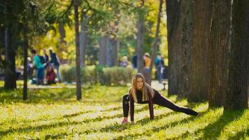 entrenamiento de fuerza de mujer fitness haciendo ejercicio en el soleado parque de otoño. Una chica deportiva caucásica en forma ejerciendo su cuerpo foto