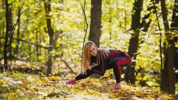 mujer haciendo ejercicios de fitness al aire libre. estiramiento femenino en el bosque de otoño. chica delgada en el entrenamiento - sentadillas foto