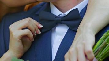 Young bride and groom are kissing in a sunny park, close up photo