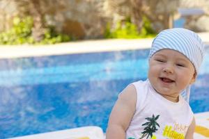 A handsome, little boy sits on a sun lounger by the pool. Selective focus. photo