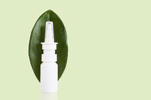 Medicinal nasal spray, green leaf on a white background. Copy space. photo